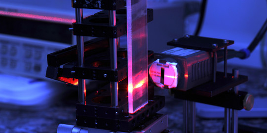 Eine Detailaufnahme eines Lasers im Labor in roten und blauen Farben.