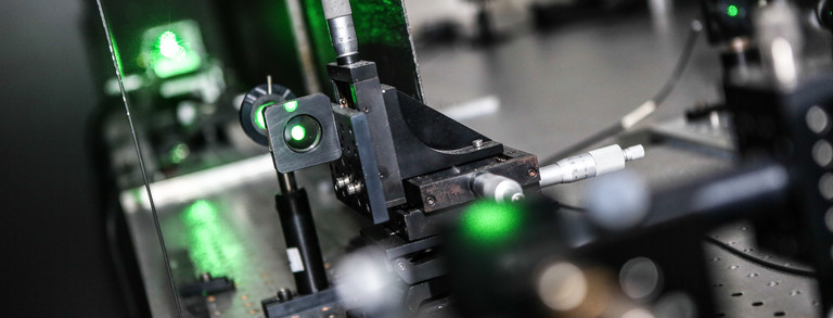 Eine Detailaufnahme eines Lasers im Labor in grünen Farben.