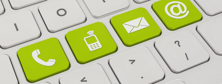A white keyboard with four green keys. On the green keys are symbols like a telephone, a cell phone, an envelope and an „@“